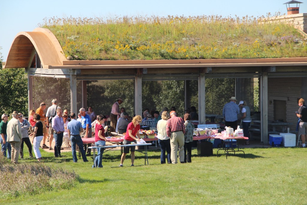 Outdoor gathering at The Pavilion with a green roof, featuring guests enjoying food and conversation on a sunny day.